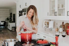 A happy woman using a kitchen gadget with a bright, modern kitchen background.