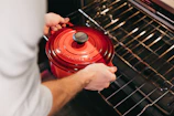Chef placing a pot into a combined oven, emphasizing the high gastronomy technique used.