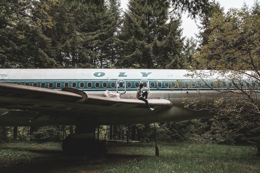 man sitting on white and green jetliner wing