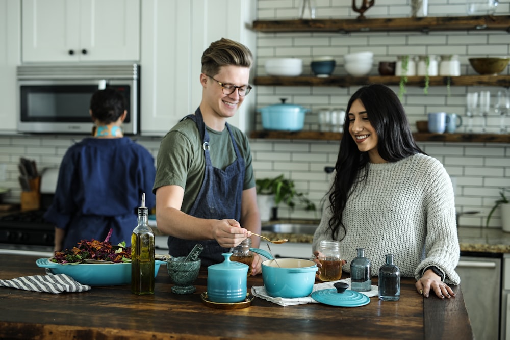 homme souriant debout et mélangeant près de la femme dans la cuisine de la maison