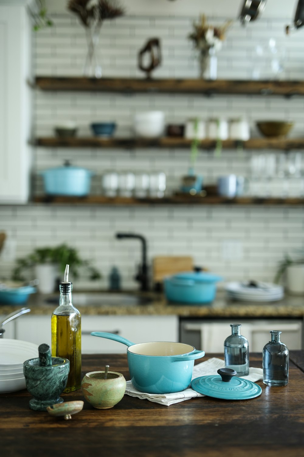 blue and white casserole near olive oil bottle on table