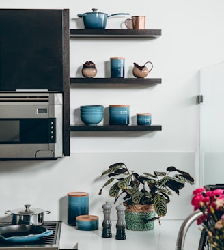 microwave beside containers on floating shelves