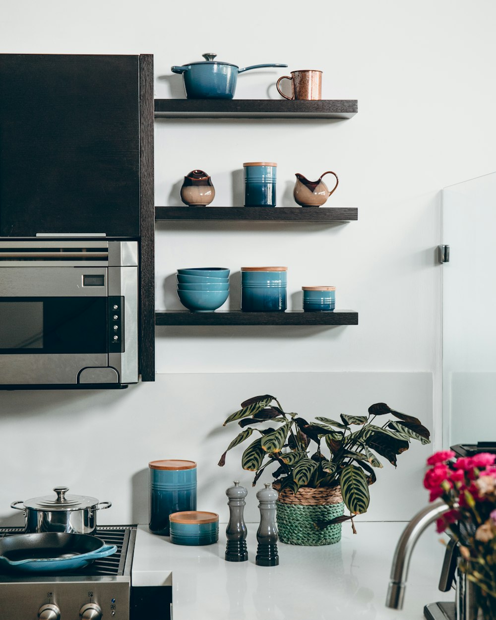 microwave beside containers on floating shelves