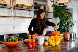 woman standing in front of fruits holding pot's lid