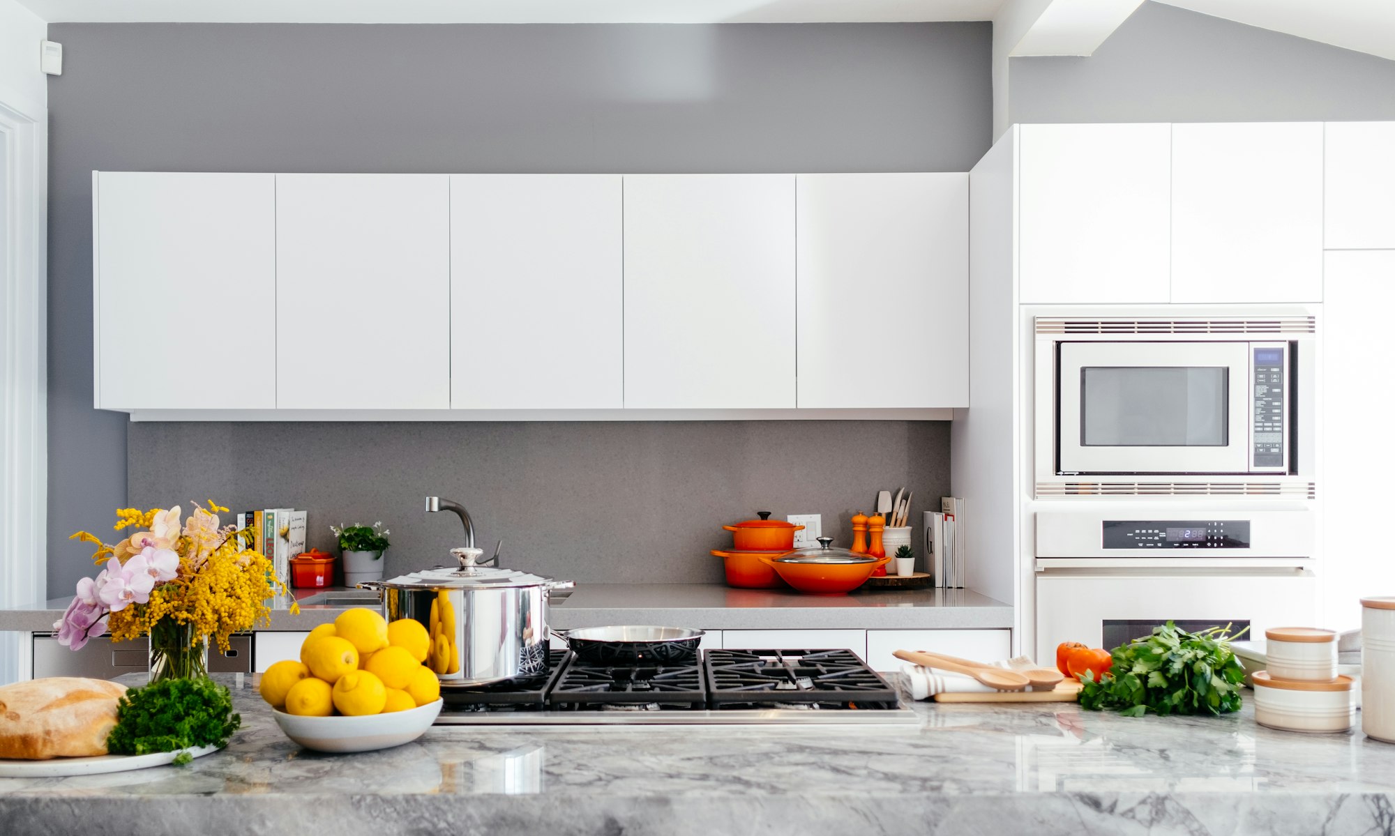 A kitchen with fruits and vegetables on the countertop.