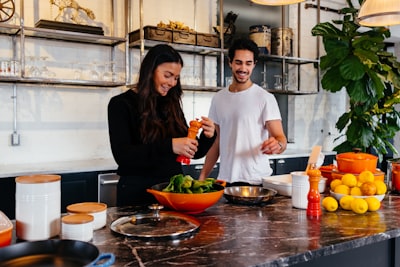 man and woman standing in front of table cook teams background