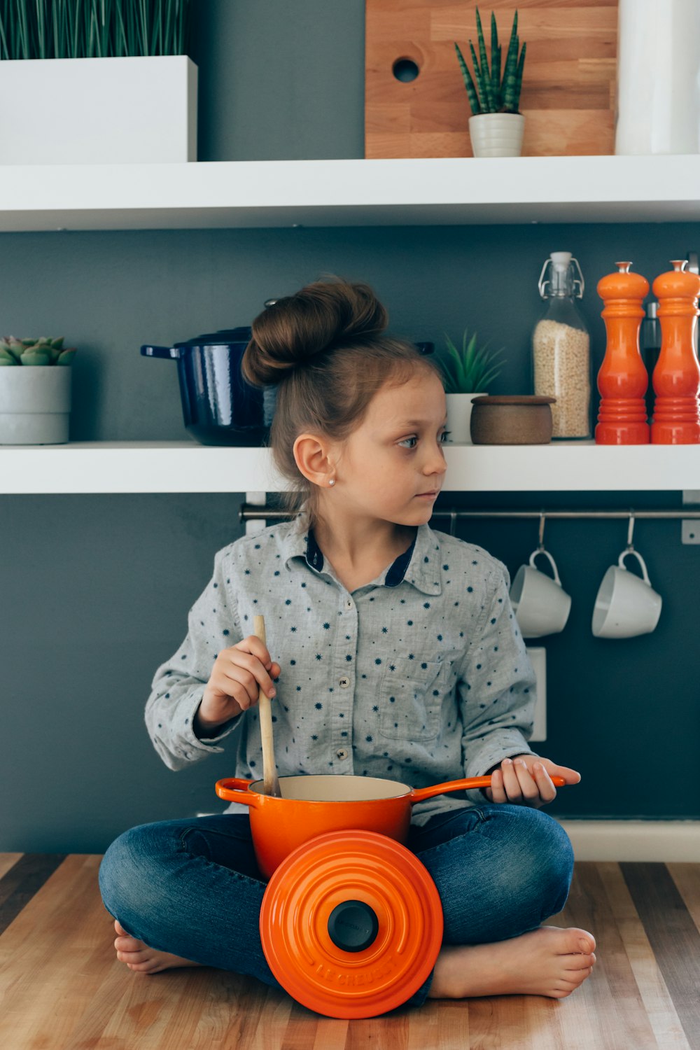 woman wearing grey blouse holding orange sauce pan and brown ladle