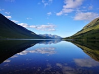 A serene mountain lake mirroring the clear blue sky and surrounding peaks.