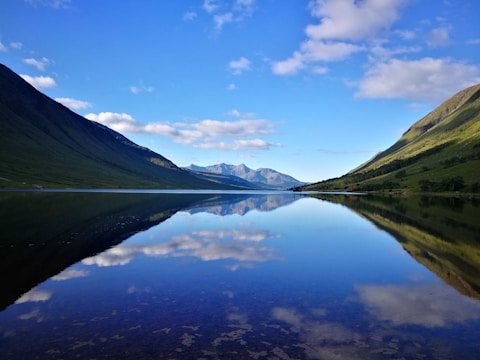 A serene mountain lake reflecting the clear blue sky and surrounding peaks.