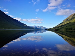 A serene mountain lake reflecting the clear blue sky and surrounding peaks.