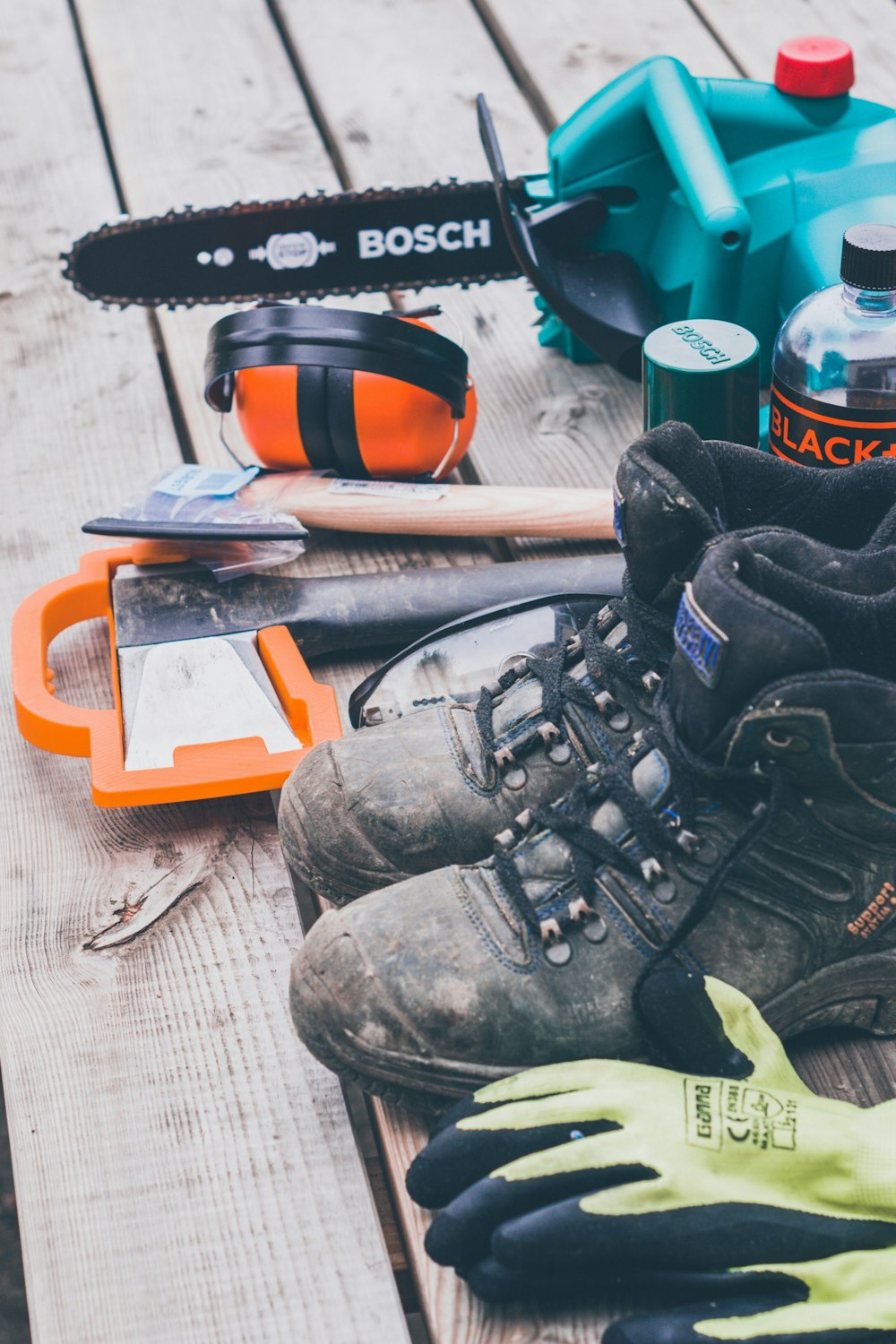 Paar Arbeitsstiefel neben Handschuhen und Handwerkzeugen