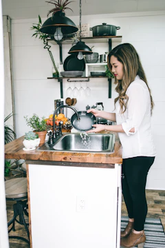 woman wearing white blouse washing dish on the faucet