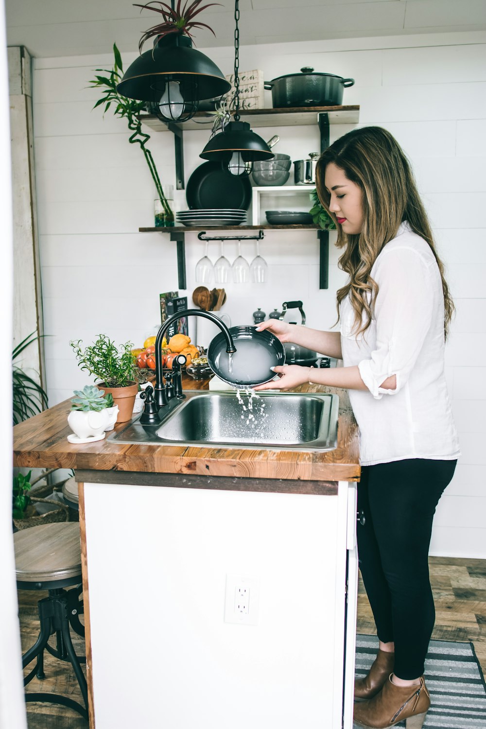 femme portant un chemisier blanc lavant le plat sur le robinet