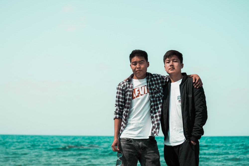 two men standing near body of water