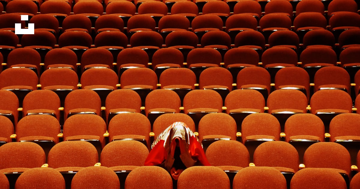 person with red jacket alone inside theater photo