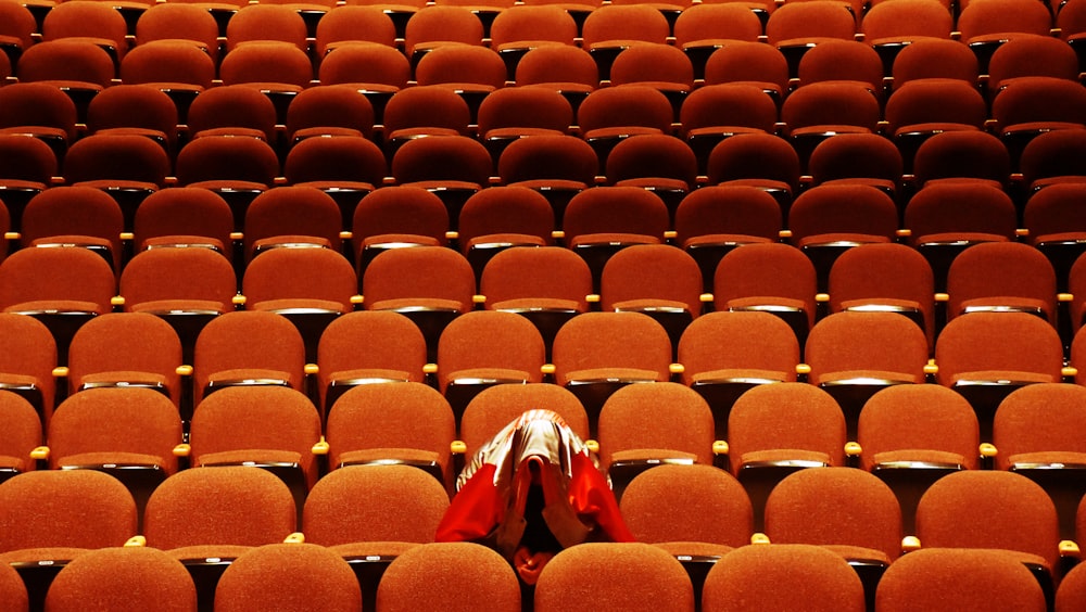 person with red jacket alone inside theater