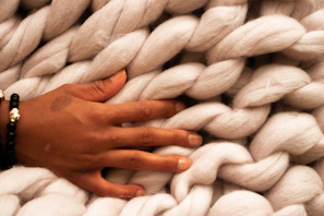 Close-up of hands holding a thick, soft wool felt pad in natural light