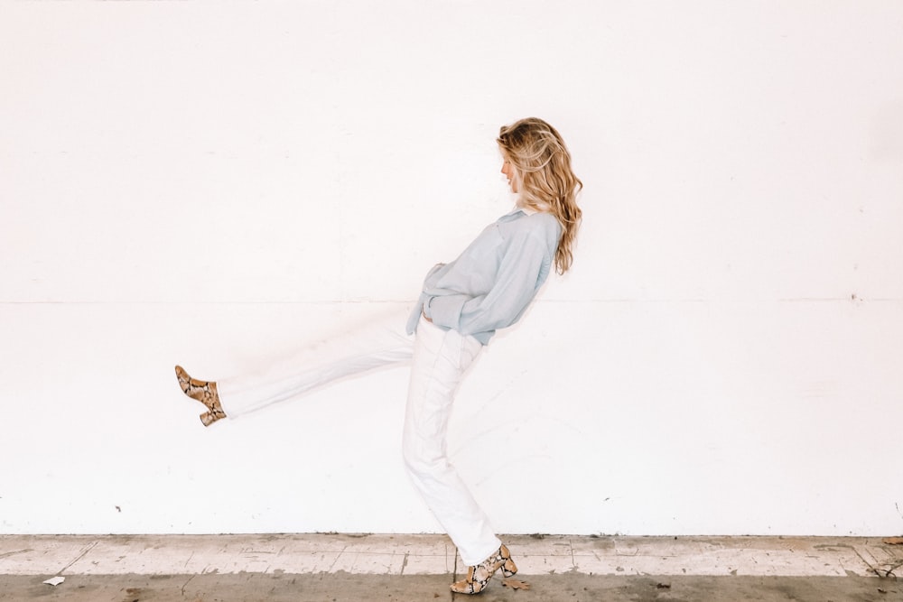 woman taking large step beside wall