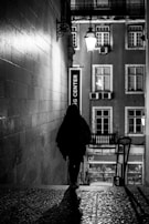 Giggs walking through a dimly lit alley, the city’s night glow behind him.