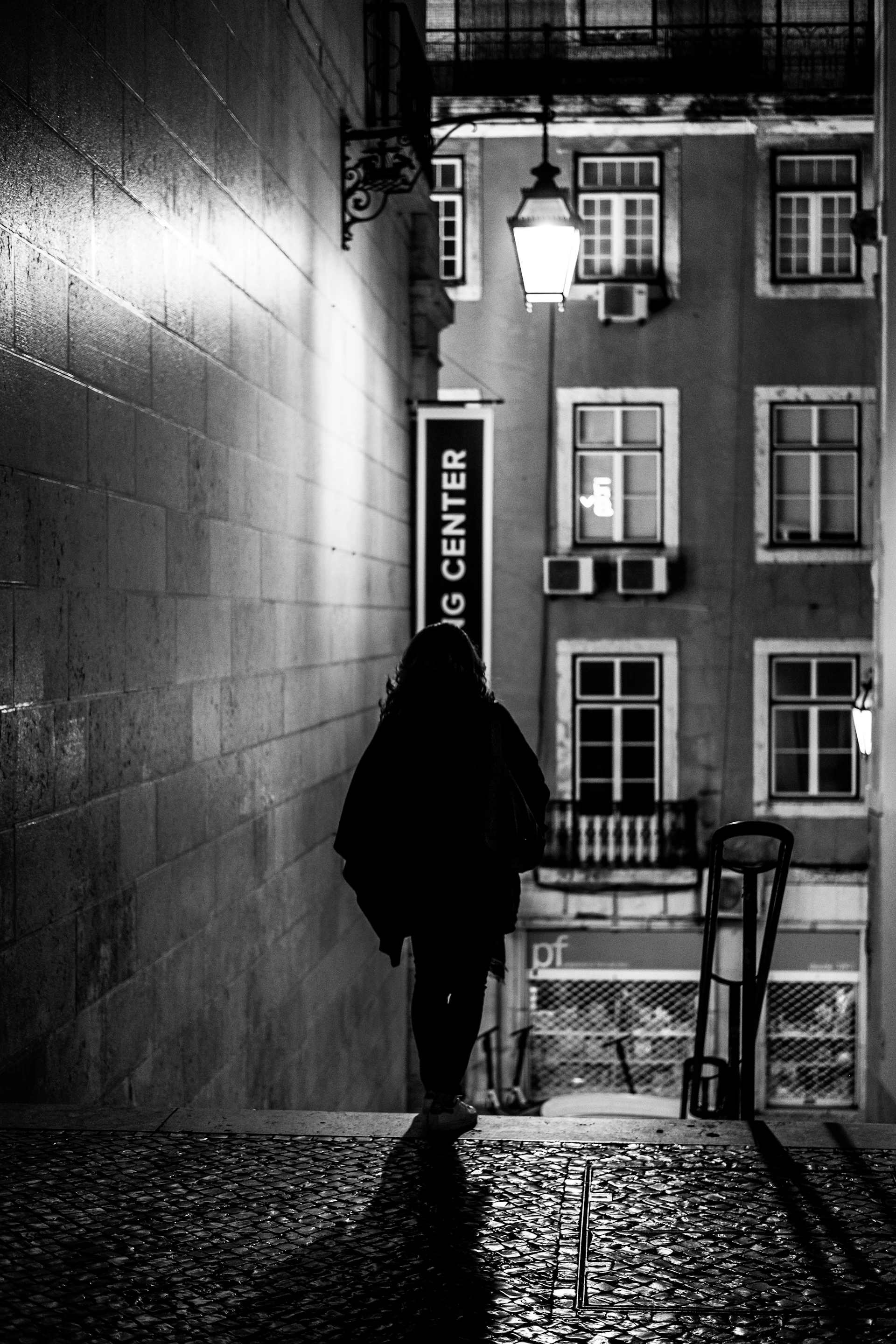 A cinematic shot of a quiet, charcoal-toned urban alley where a solitary figure reflects thoughtfully, bathed in moody twilight.