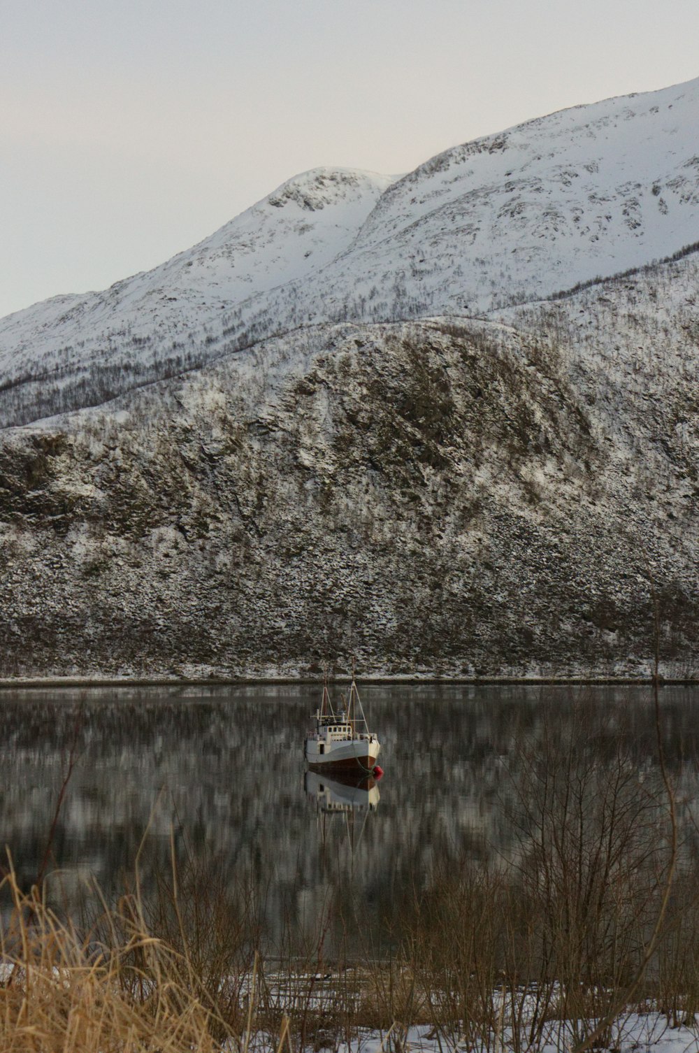 white boat near snow-covered mountain