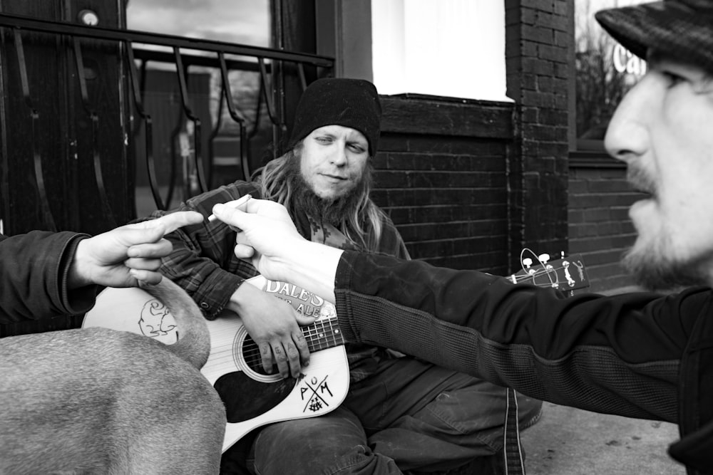 greyscale photo of man playing guitar