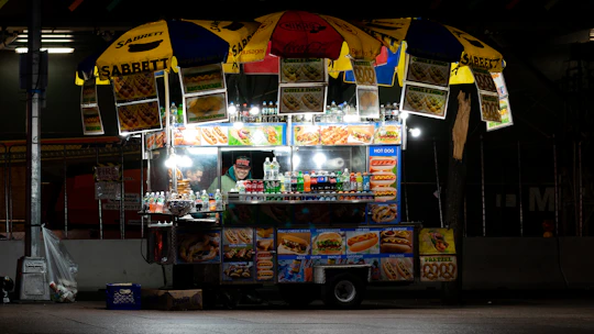 A vibrant food cart setup at sunset with customers enjoying takoyaki under warm lights.