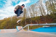 Photo of a skateboarder mid-air during a trick at an outdoor skate park.