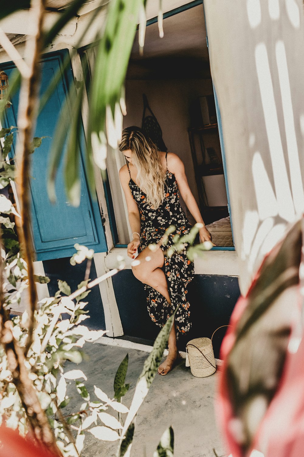 woman wearing floral dress sitting on window