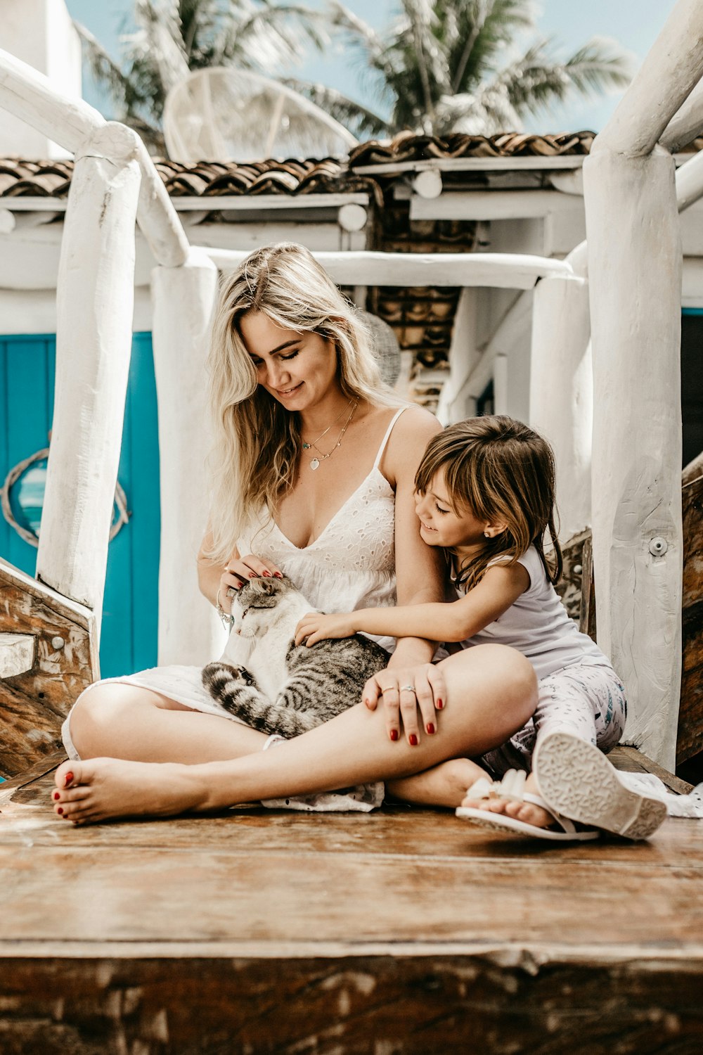 women sitting beside girl while carrying gay cat during daytime