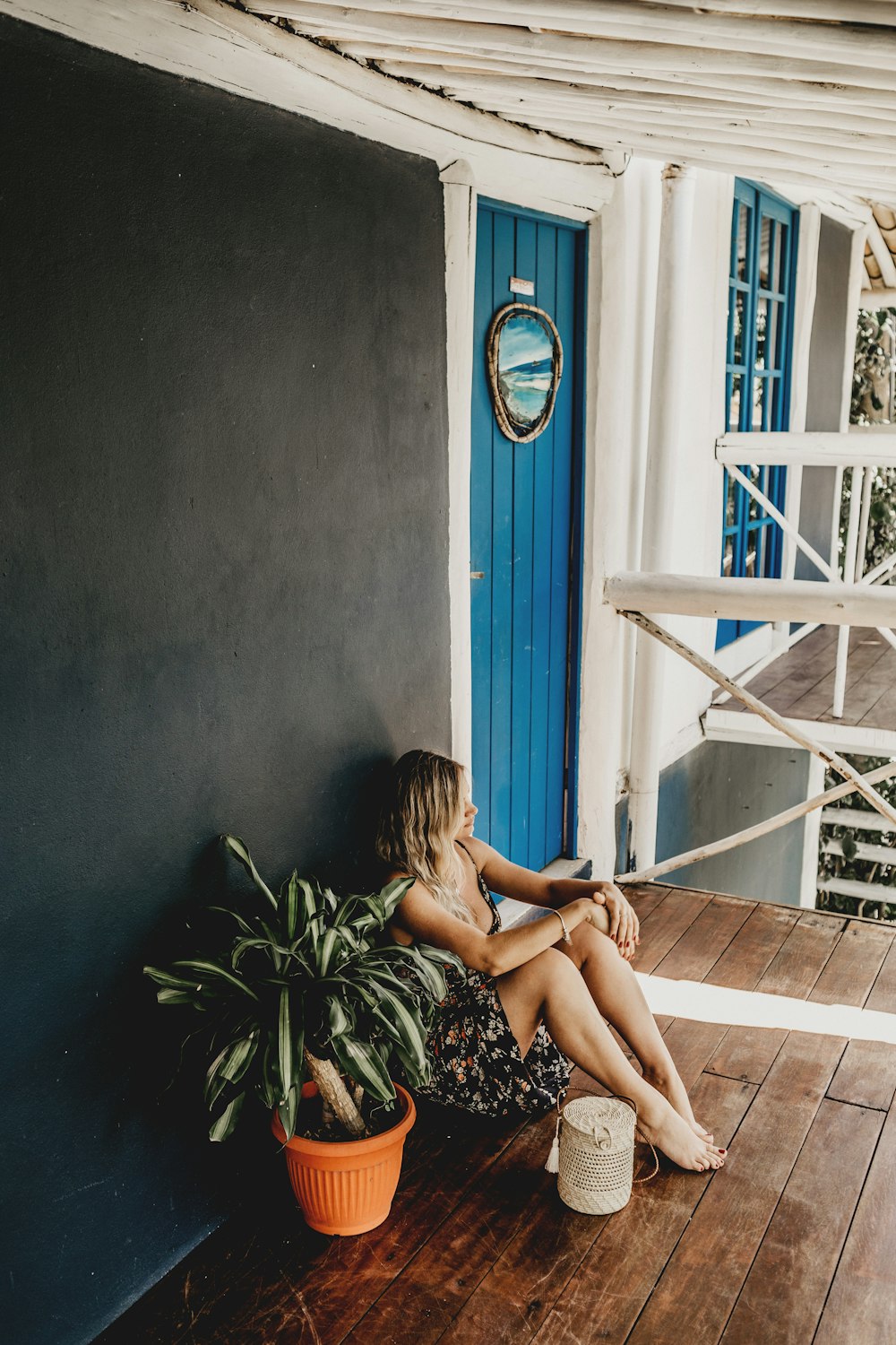 woman sitting on brown wooden porch floor