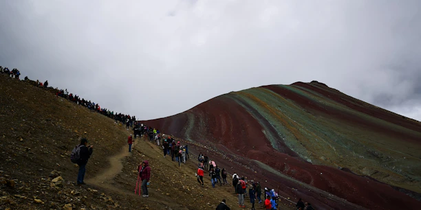 Group of happy travelers hiking the colorful trails of the Rainbow Mountain.