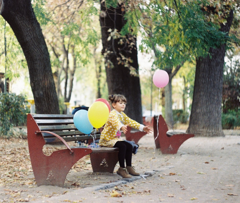 girl sitting on brown wooden bench during daytime