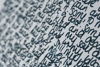 Close-up view of handwritten text on a white surface. The words are written in a dense and flowing script, with limited spacing between each line and word. The ink appears to be a dark blue or black color, creating a stark contrast against the light background.