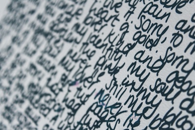 Close-up view of handwritten text on a white surface. The words are written in a dense and flowing script, with limited spacing between each line and word. The ink appears to be a dark blue or black color, creating a stark contrast against the light background.