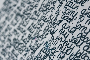 Close-up view of handwritten text on a white surface. The words are written in a dense and flowing script, with limited spacing between each line and word. The ink appears to be a dark blue or black color, creating a stark contrast against the light background.