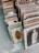 A collection of vintage framed photographs is arranged on the ground. The frames vary in style and size, showcasing sepia-toned portraits, including a child in traditional attire and a person in formal clothing. The setting appears to be an outdoor market or antique shop.