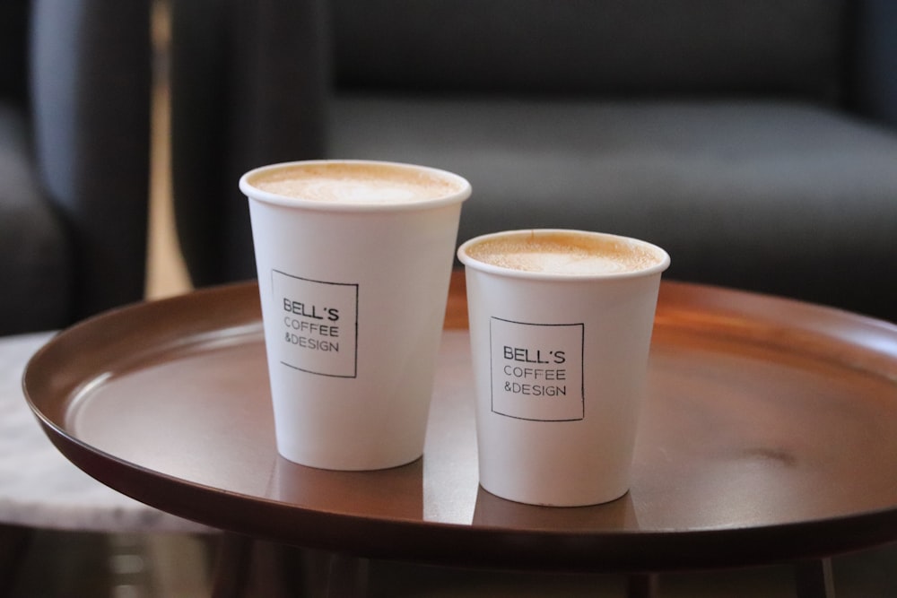 two white disposable cups on brown wooden tray