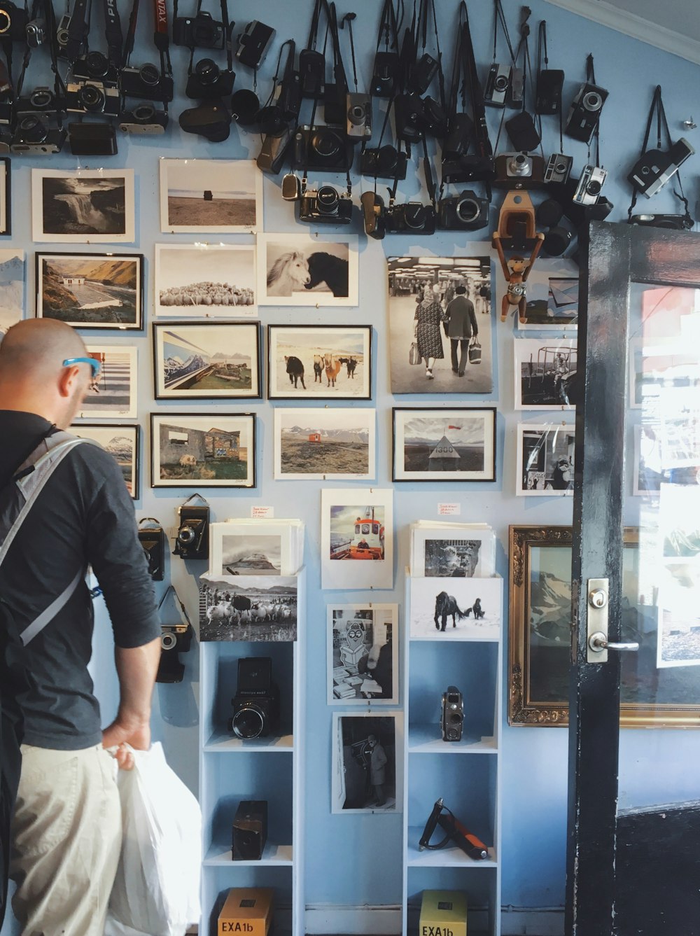 person wearing black long-sleeved shirt standing in front of assorted photos