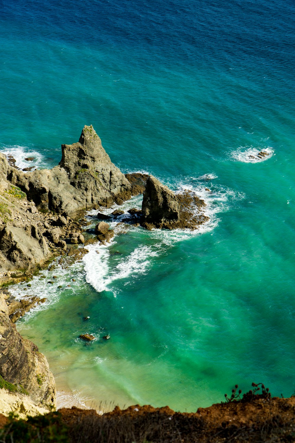 aerial photography of mountain cliff beside seashore during daytime