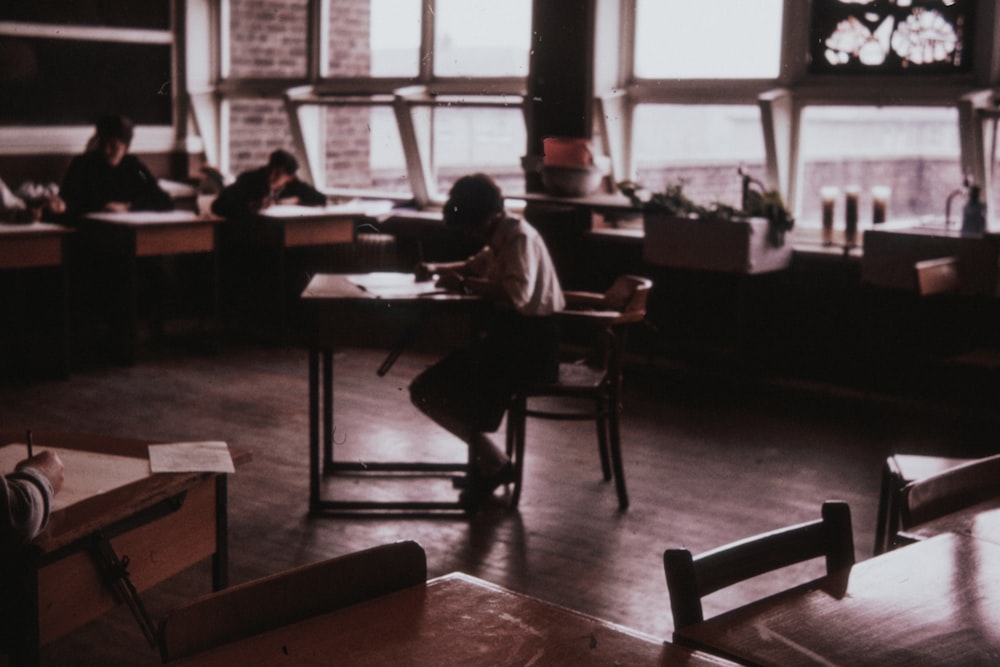 man sitting on chair in front of study table in middle of room