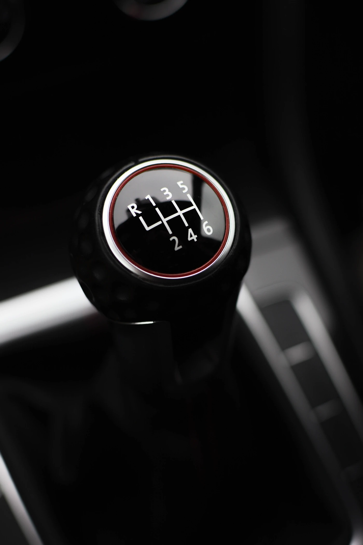 Close-up of a manual transmission gear shifter inside a car, showing the H-pattern shift knob