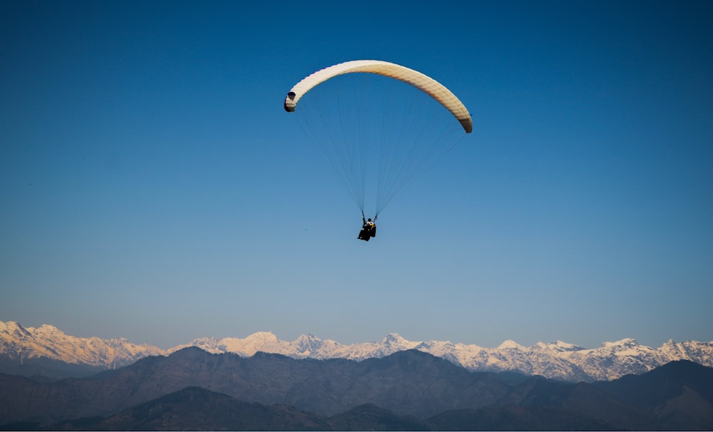 person paragliding near snow mountain