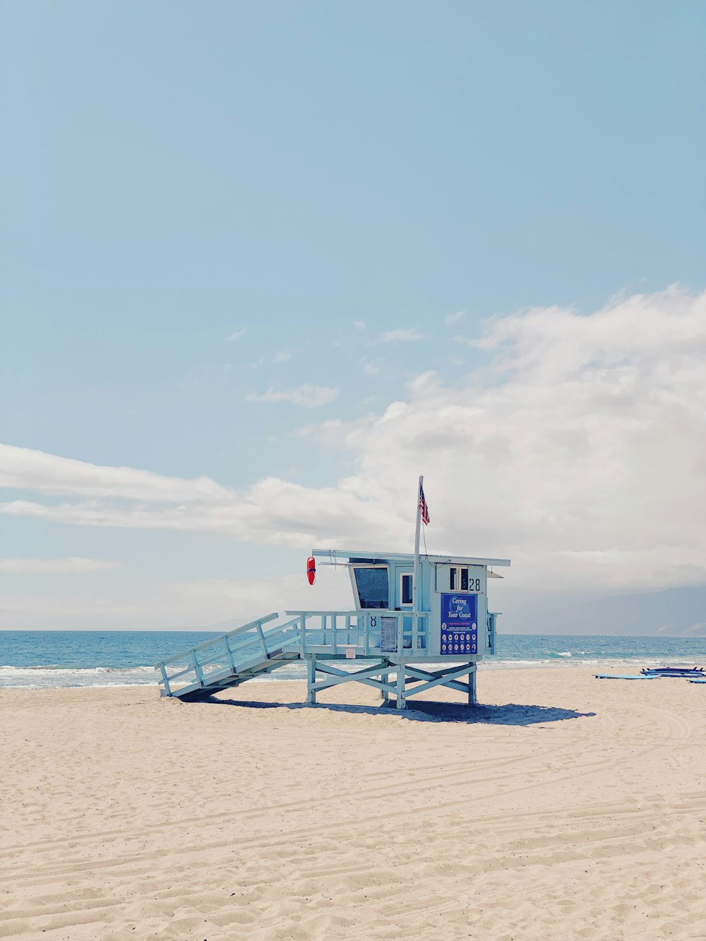 Photographie d’un bâtiment blanc sur du sable brun au bord de la mer pendant la journée