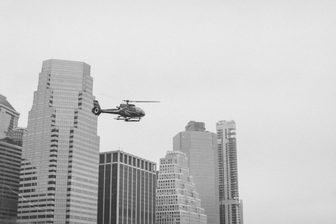 photography of helicopter during flight passed by high-rise buildings