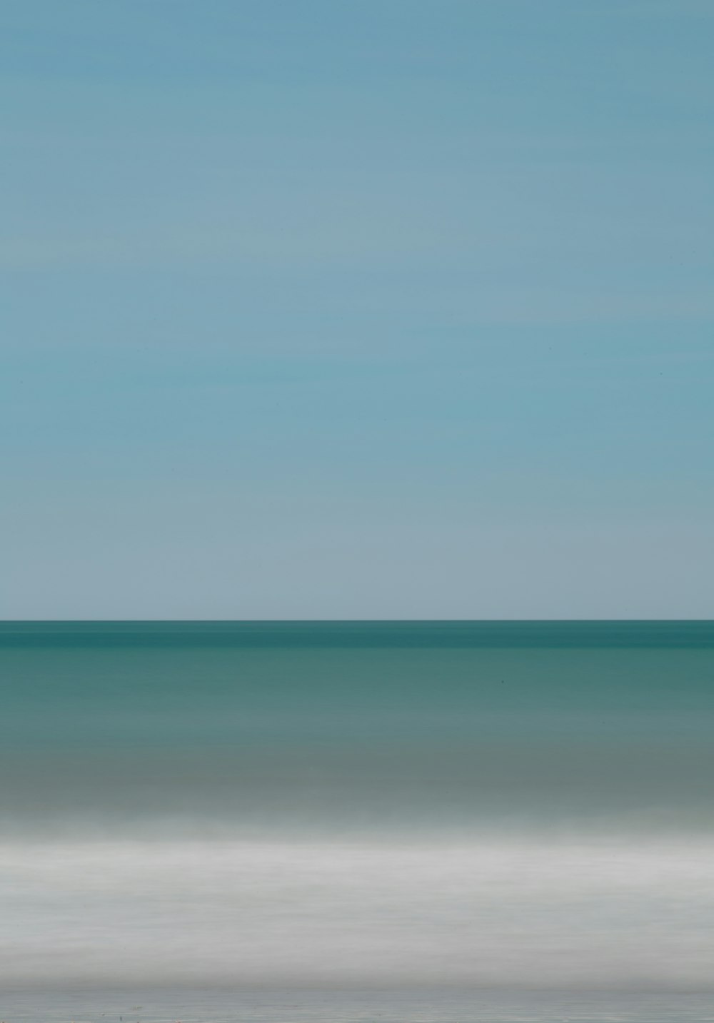 uma foto desfocada do oceano com um barco solitário ao longe