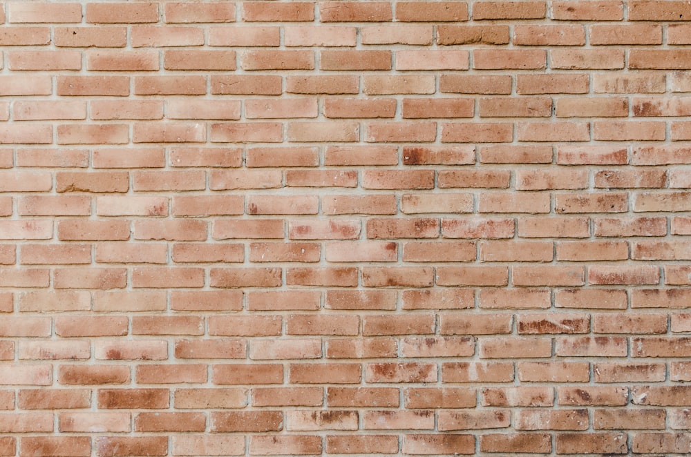 une borne d’incendie rouge assise devant un mur de briques