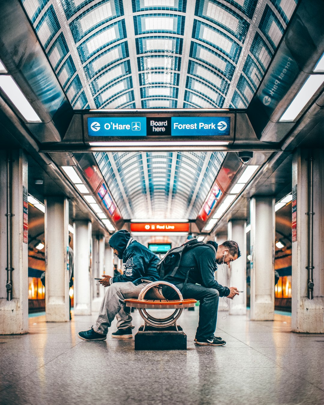 two men sitting on bench in subway station