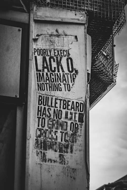 Black and white photo of a gritty urban mural with bold typography overlay.