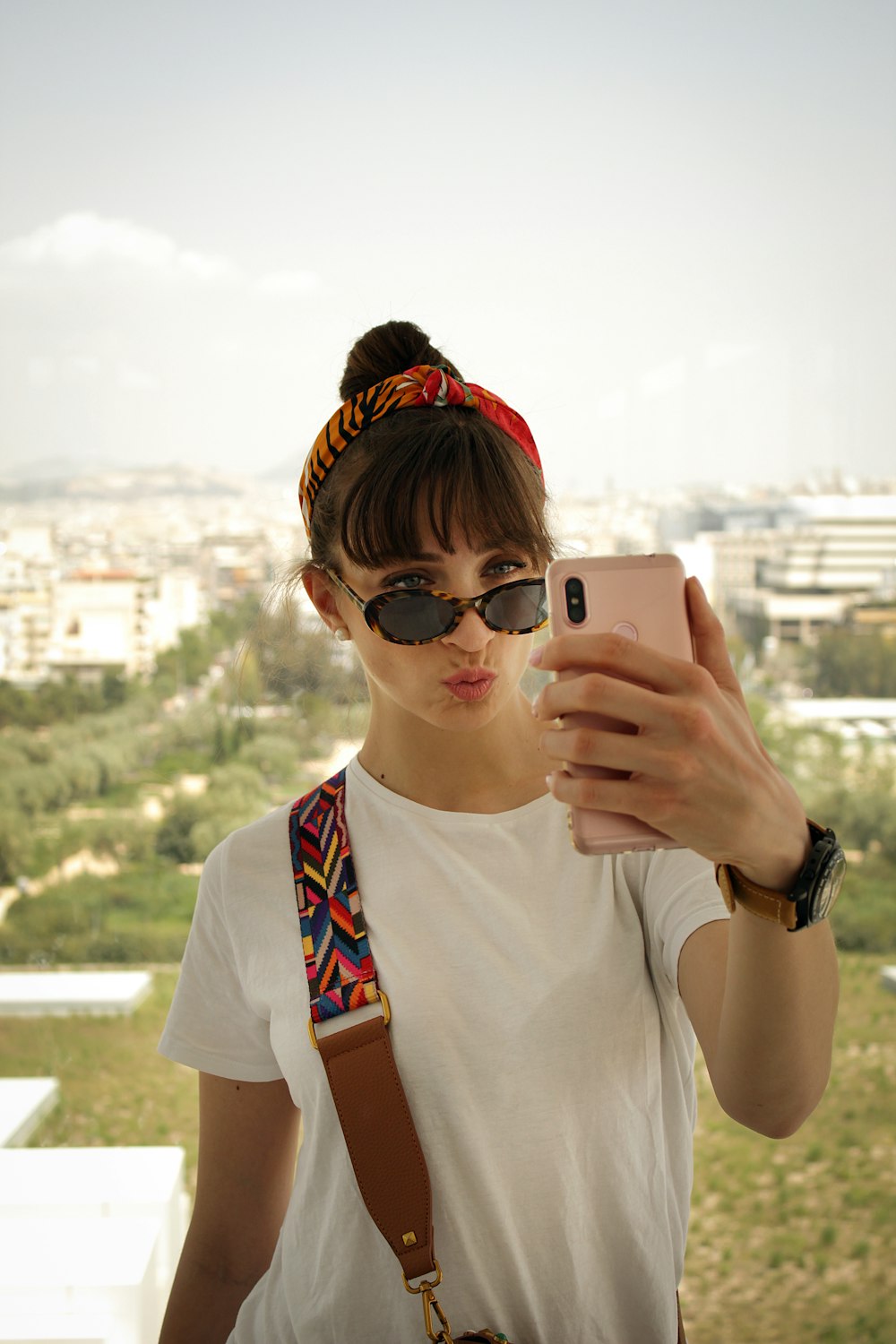 woman pouting her lips while holding smartphone in front of her face